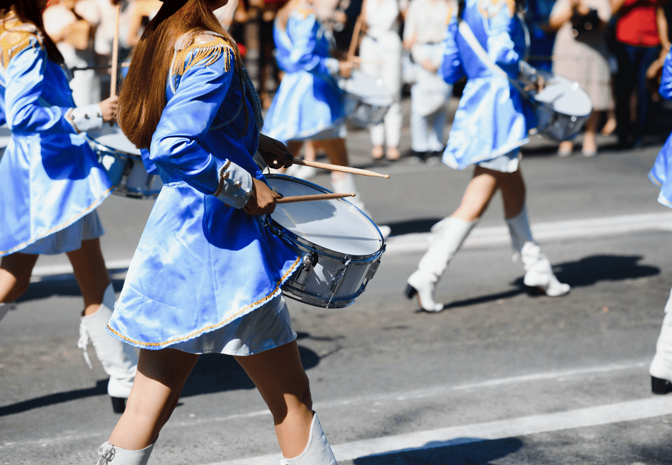 majorettes with white and blue uniforms perform in the streets of the city.