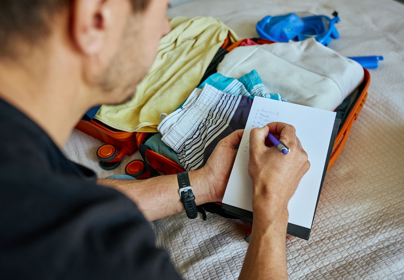 Man Making List Before Packing Suitcase at Home
