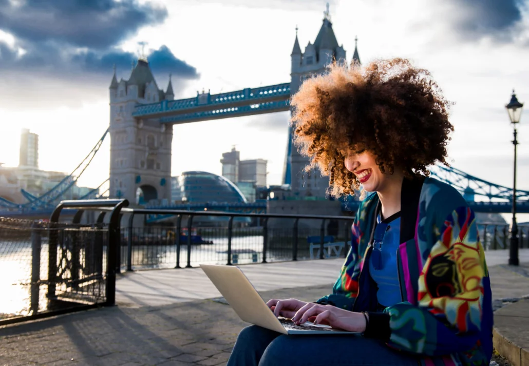 young-woman-sitting-outdoors-using-laptop-tower-bridge