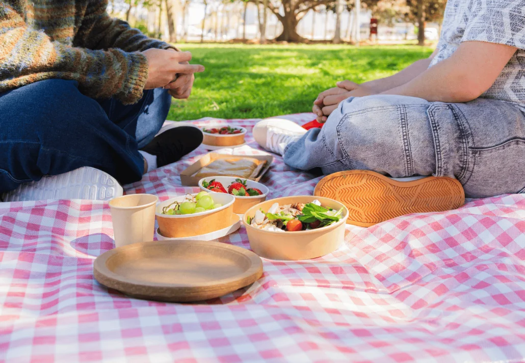 Couple enjoying a romantic picnic in the park with sustainable food containers