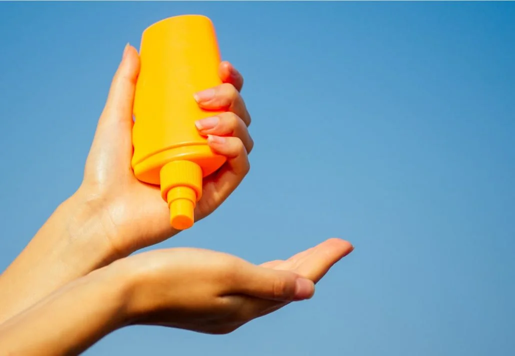 Woman applying sunscree on her hand on a sunny summer day.