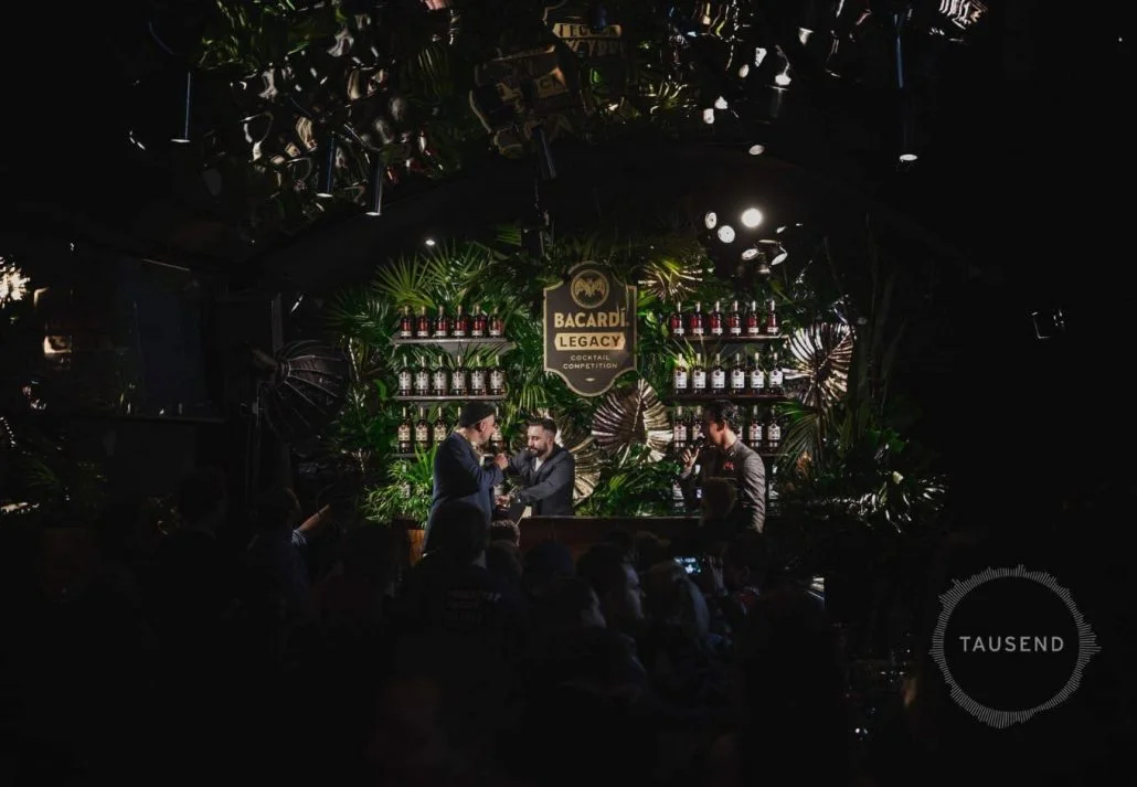 Two male singers performing in front of the crowd with a mixologist in the background in Tausend Bar, Berlin