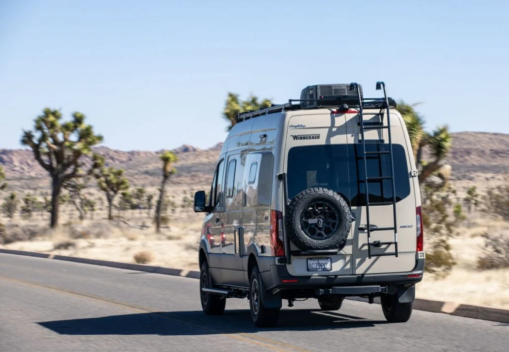 A Winnebago Mercedes Sprinter Van drives through Joshua Tree National Park on a sunny day. 