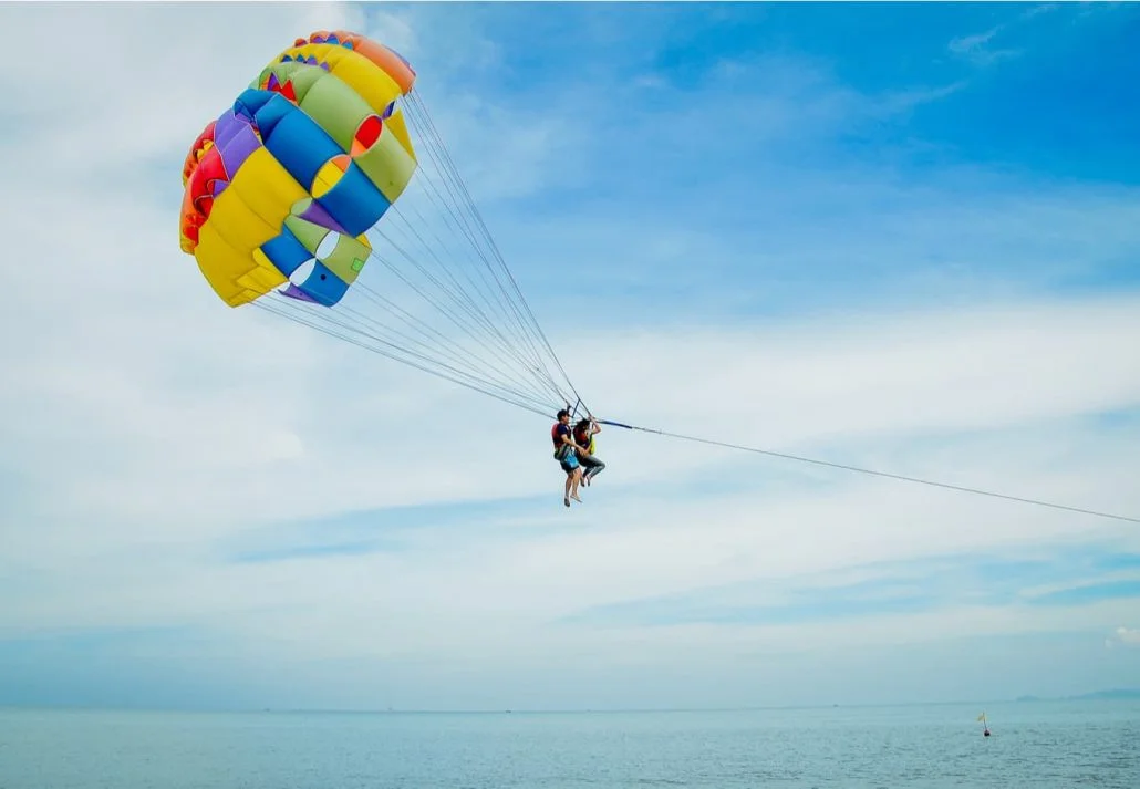 Tourists parasailing in the blue sky over the ocean.