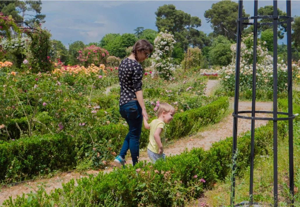 Mother and daugther strolling in a garden in In El Retiro Park, Madrid, Spain.
