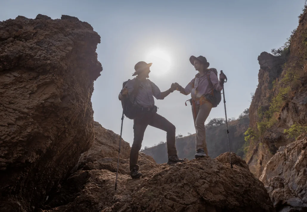 
Tourists show helping young woman with backpacks hike on rocky top mountain trekking and soft foggy
