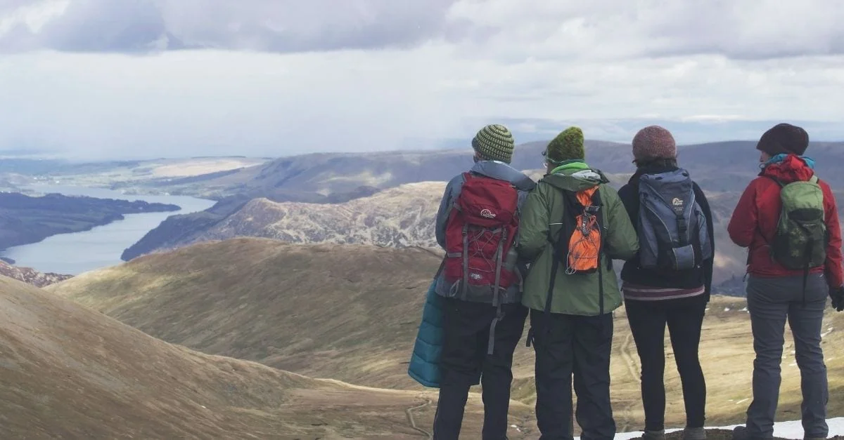 A group of 4 woman contemplanting a mountainous valley while hiking.