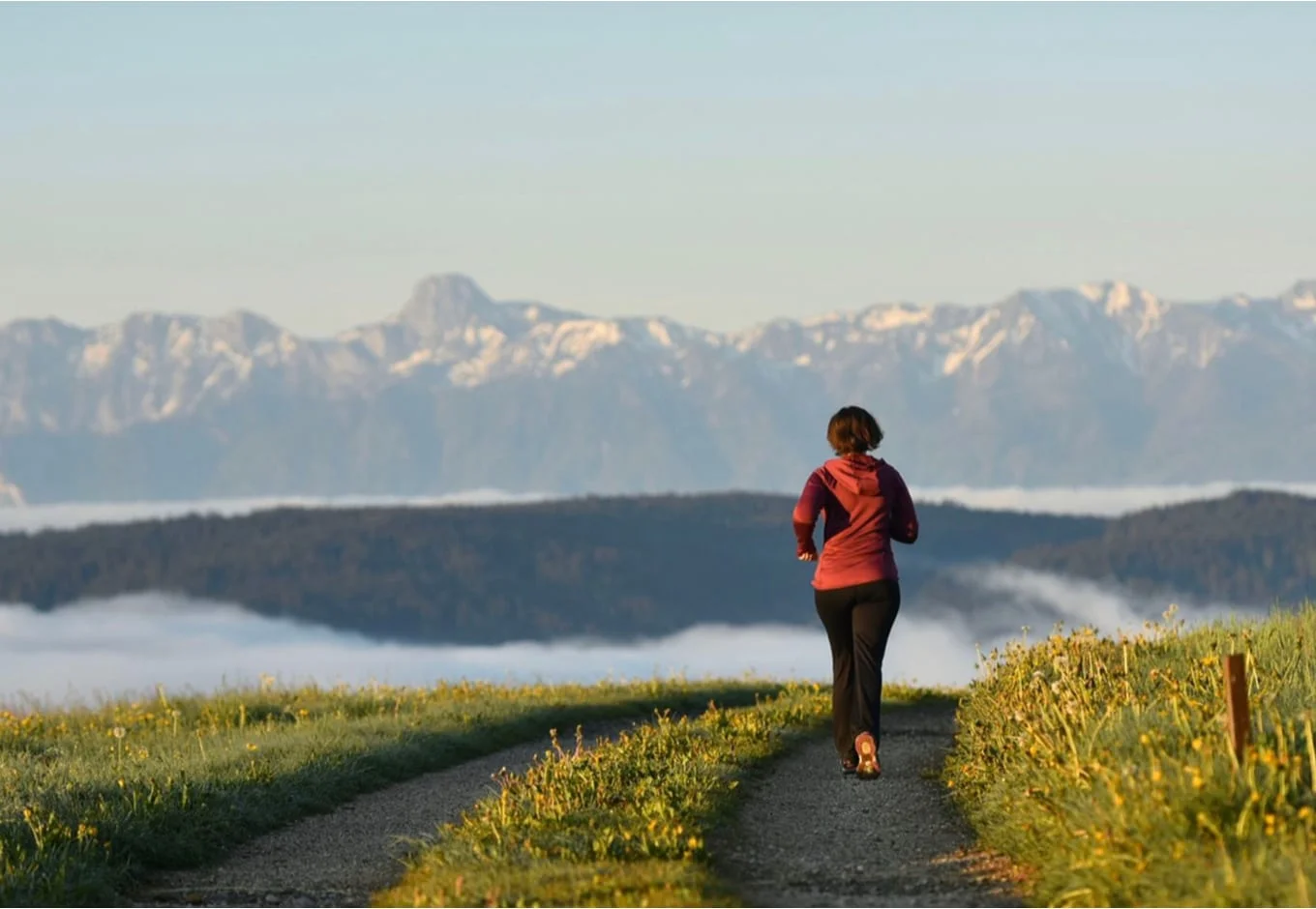 Woman running towars a snowy mountain range.