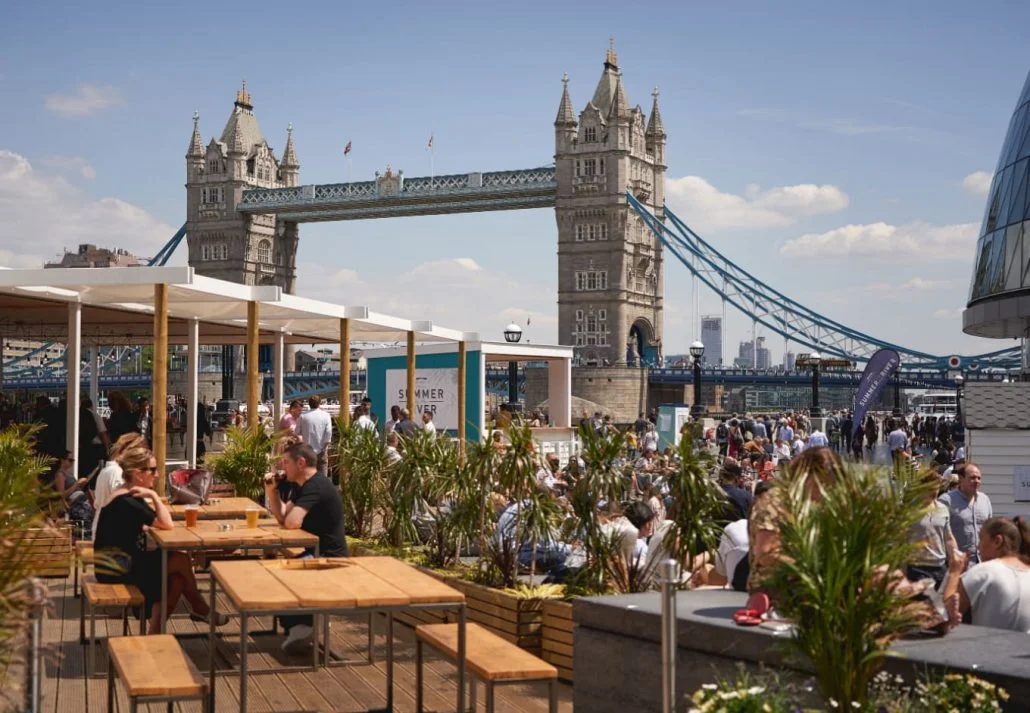 Best Time to Visit London - A rooftop bar filled with people, and offering views of the Tower Bridge of London.