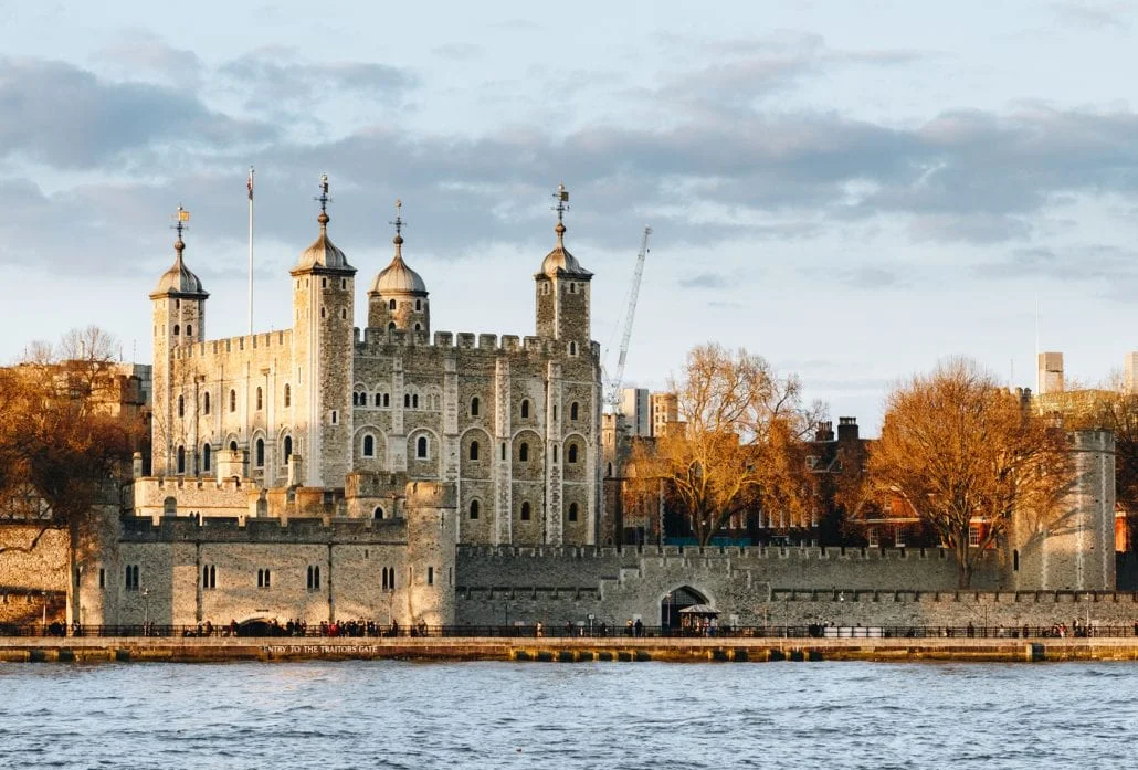 London Attractions - Tower of London at sunset, surrounded by autumn trees.