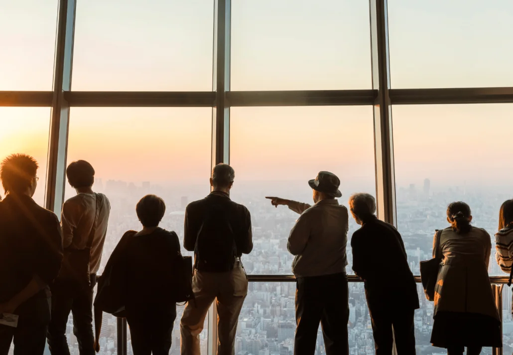 Rear view silhouette of a group of people looking onto cityscape from skyscraper window.