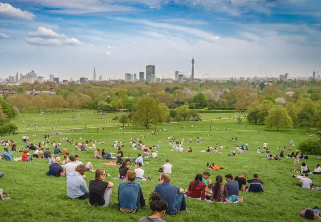 Parks in London - Breath-taking panoramic scenic view of London cityscape seen from a crowded Primrose Hill park on a sunny spring afternoon.