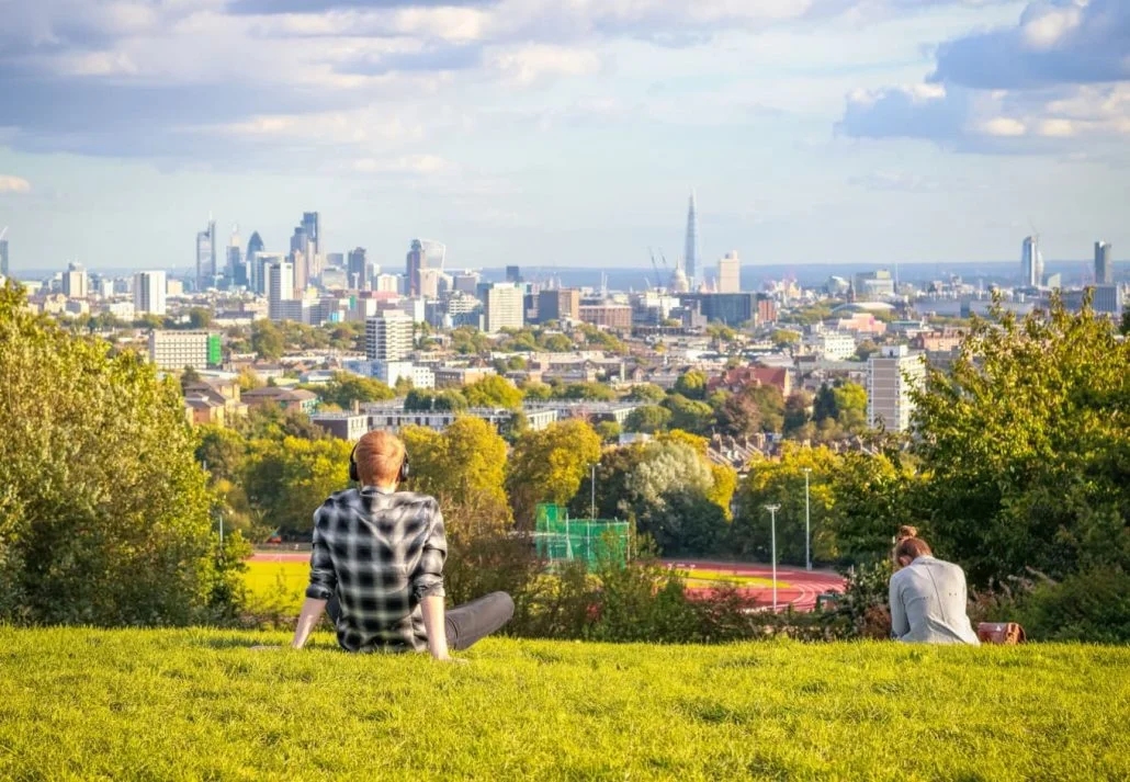 Parks in London - Back view of tourists looking over the London city skyline from Parliament Hill in Hampstead Heath.