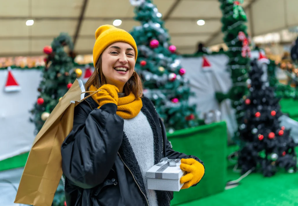 
Happy woman holding shopping bags and gift box at christmas market