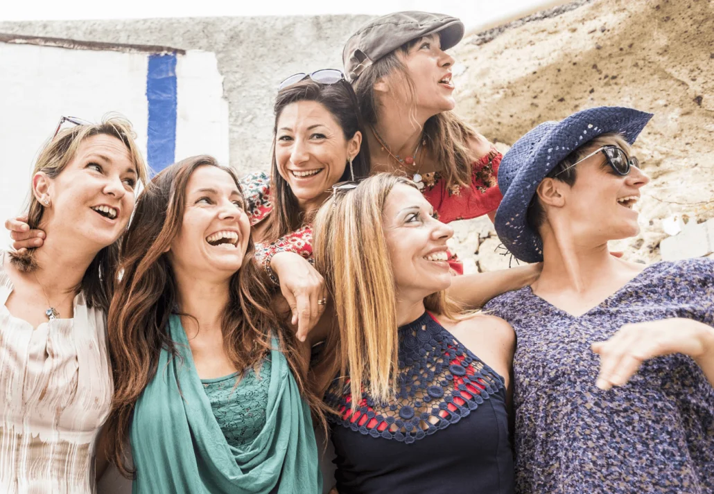 Group of cheerful happy young women hug and enjoy the outdoor leisure activity