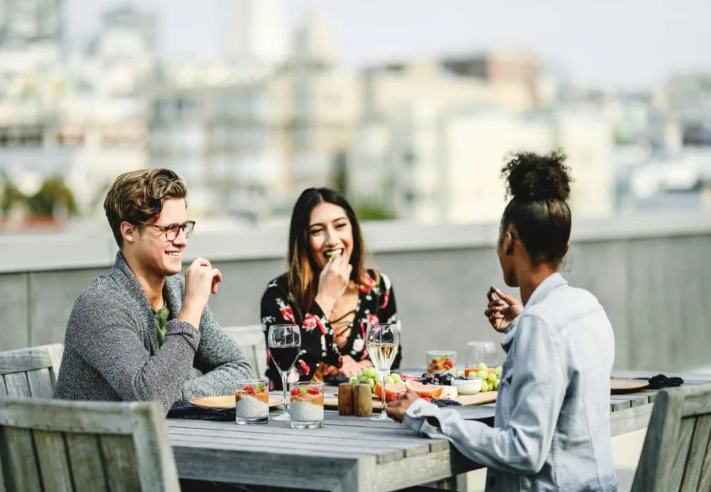 A group of friends sitting and enjoying wine on a rooftop terrace